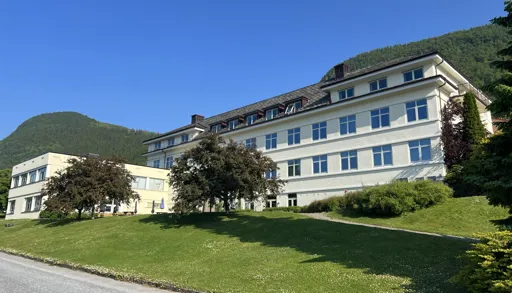 En stor sykehusbygning med en plen foran seg