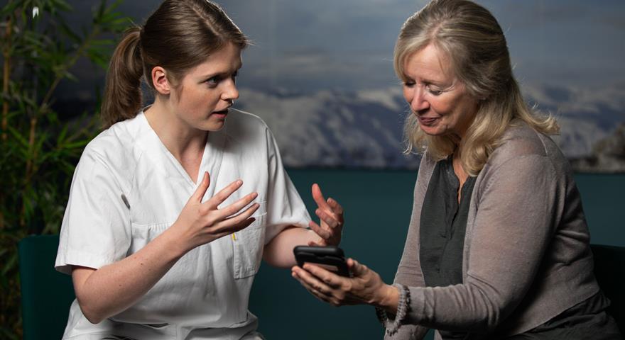 To personar som ser på ein mobiltelefon