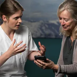 To personar som ser på ein mobiltelefon