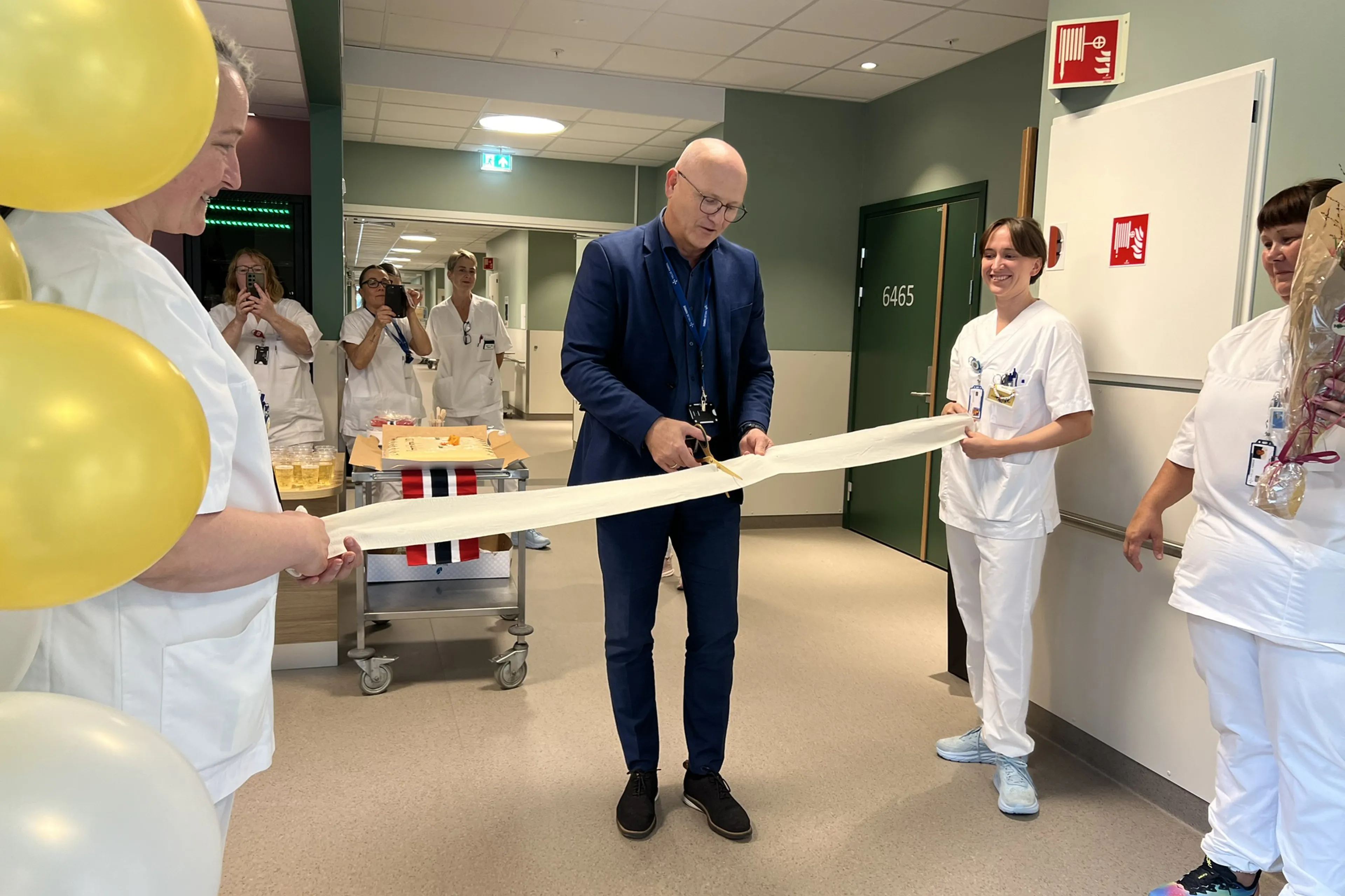 Administrerande direktør Arve Varden klipper bandasjesnora, mens to sjukepleiarar held snora, under opninga av kreft- og kirurgisk sengepost.