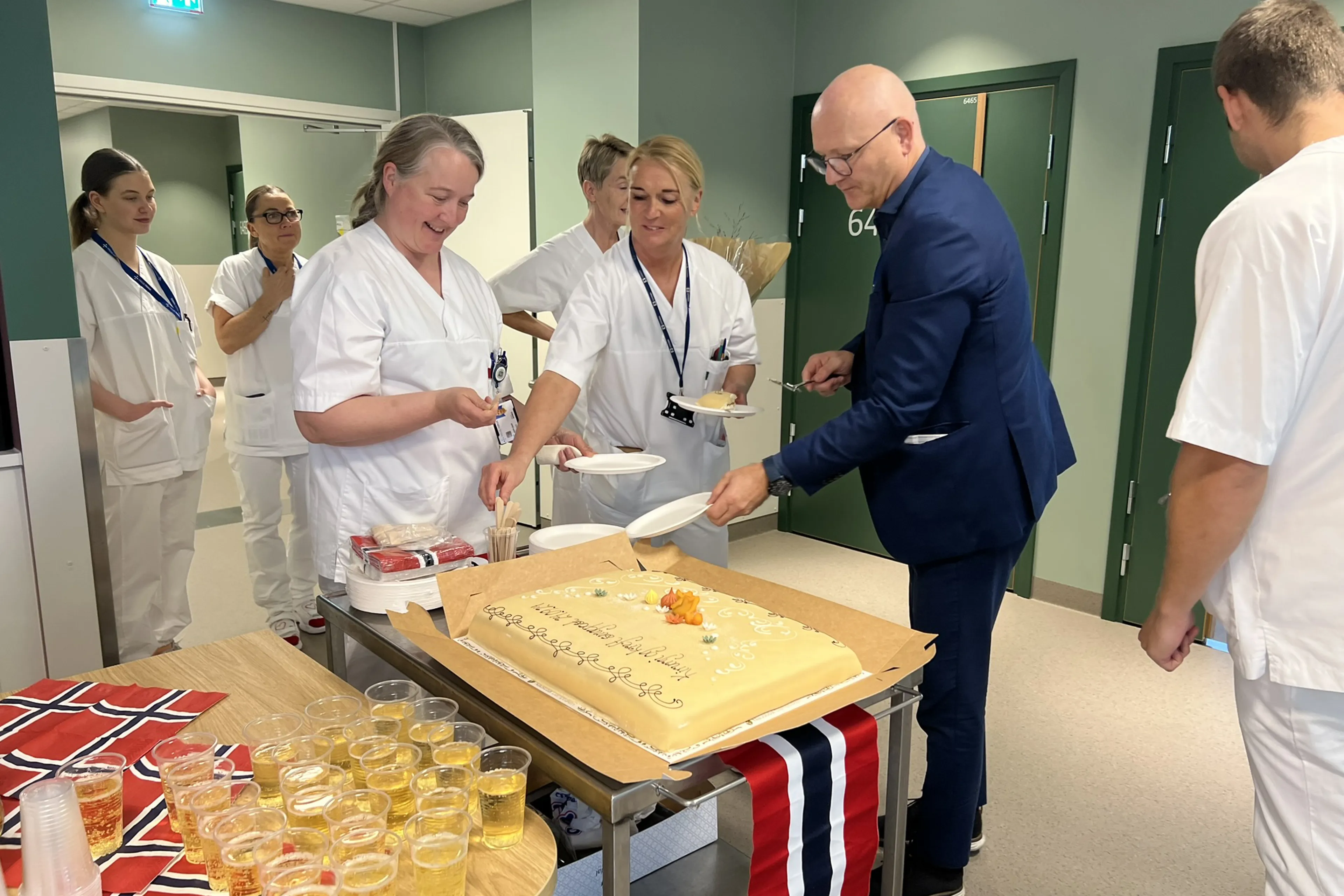 Tilsette i avdelinga, saman med administerande direktør, feirar flyttinga til Livabygget med kake, brus og norske flagg