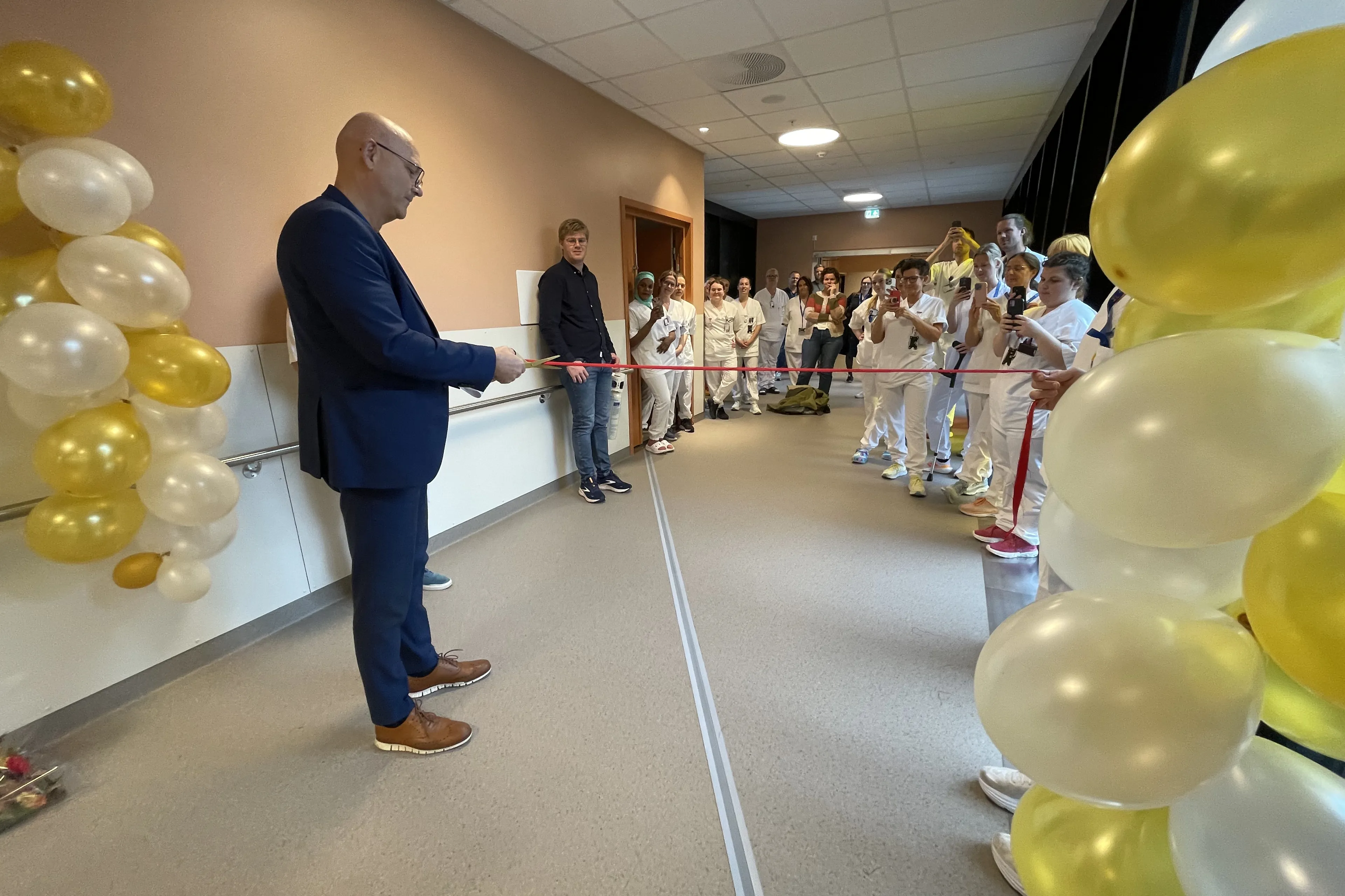 Administerande direktør Arve Varden gjer seg klar til å klippe snora i 7. etasje. Tilsette følger med, og det er pynta med ballongar.