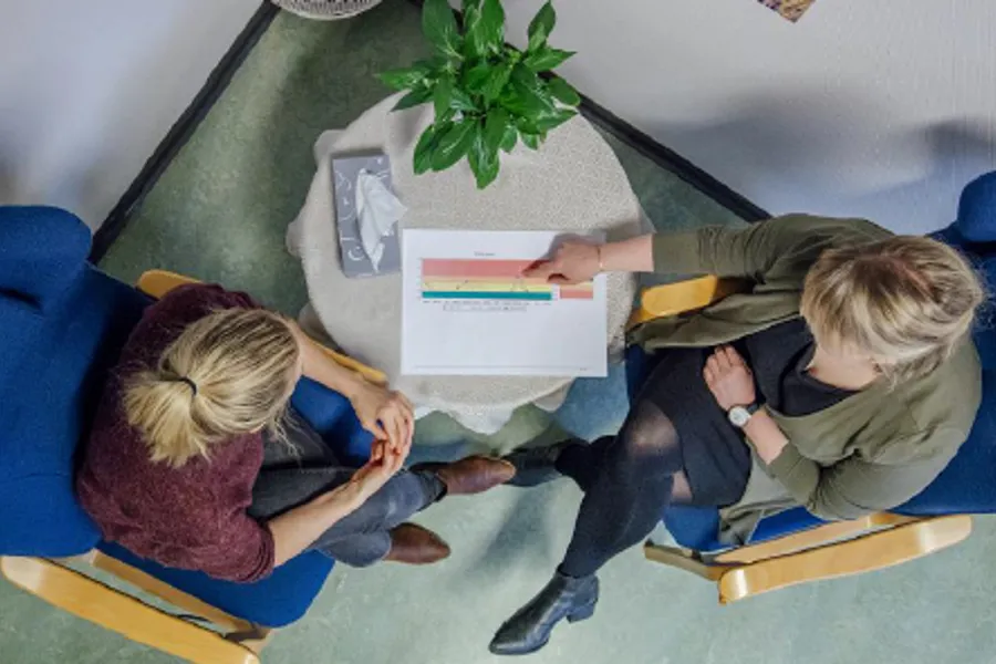 To kvinner som sit i kvar sin stol rundt eit bord, sett ovanfrå i fugleperspektiv