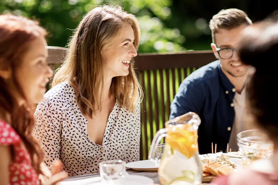 Nokre personar som sit utandørs rundt eit bord og har det hyggelig