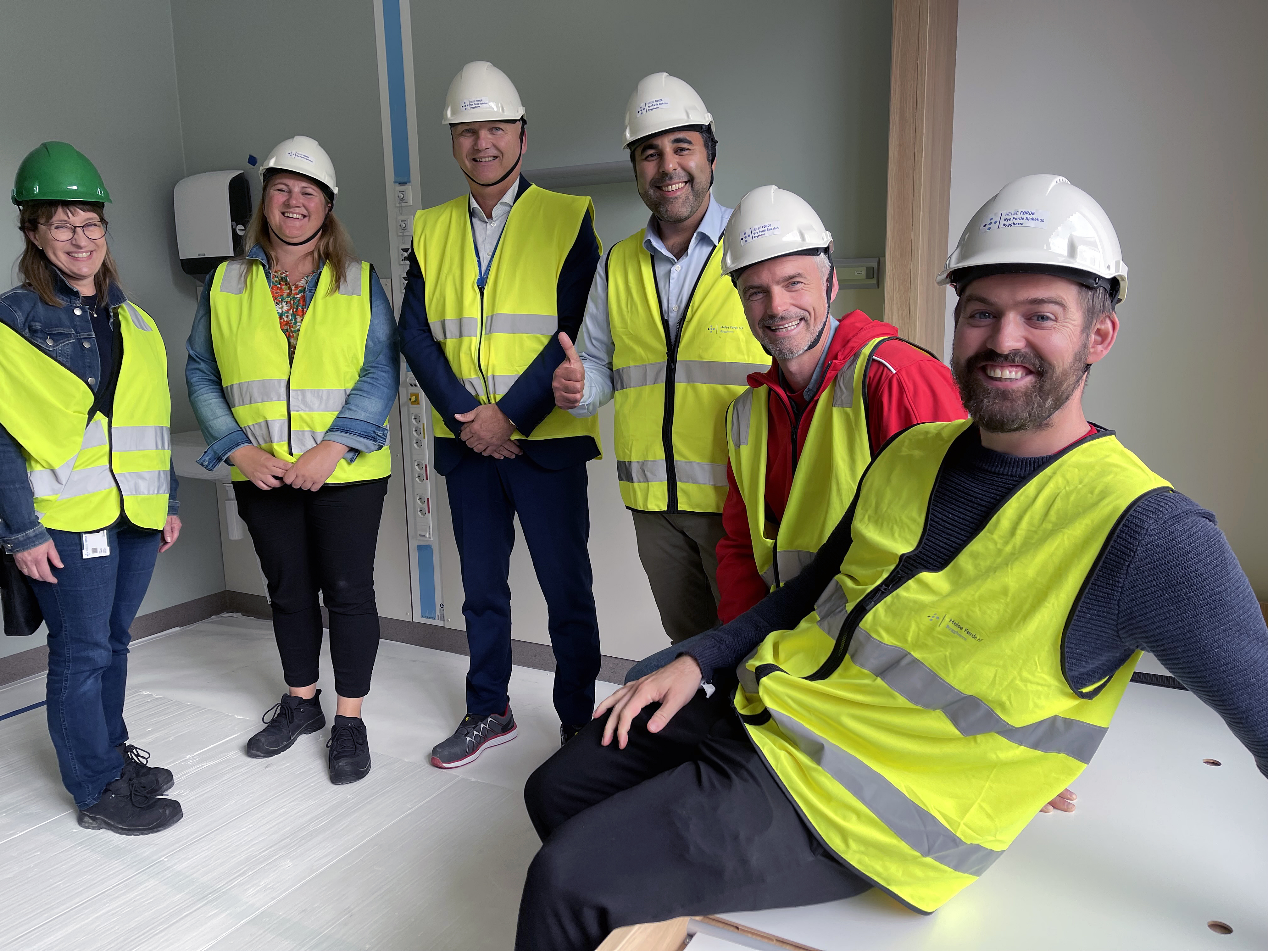 Ei gruppe menneske med sikkerheitsvestar inne i eit rom.