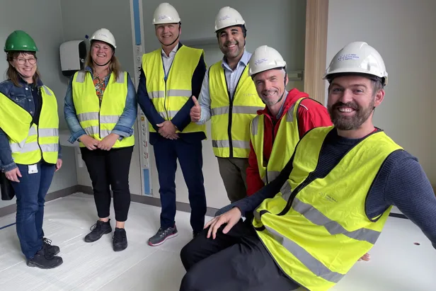 Ei gruppe menneske med sikkerheitsvestar inne i eit rom.