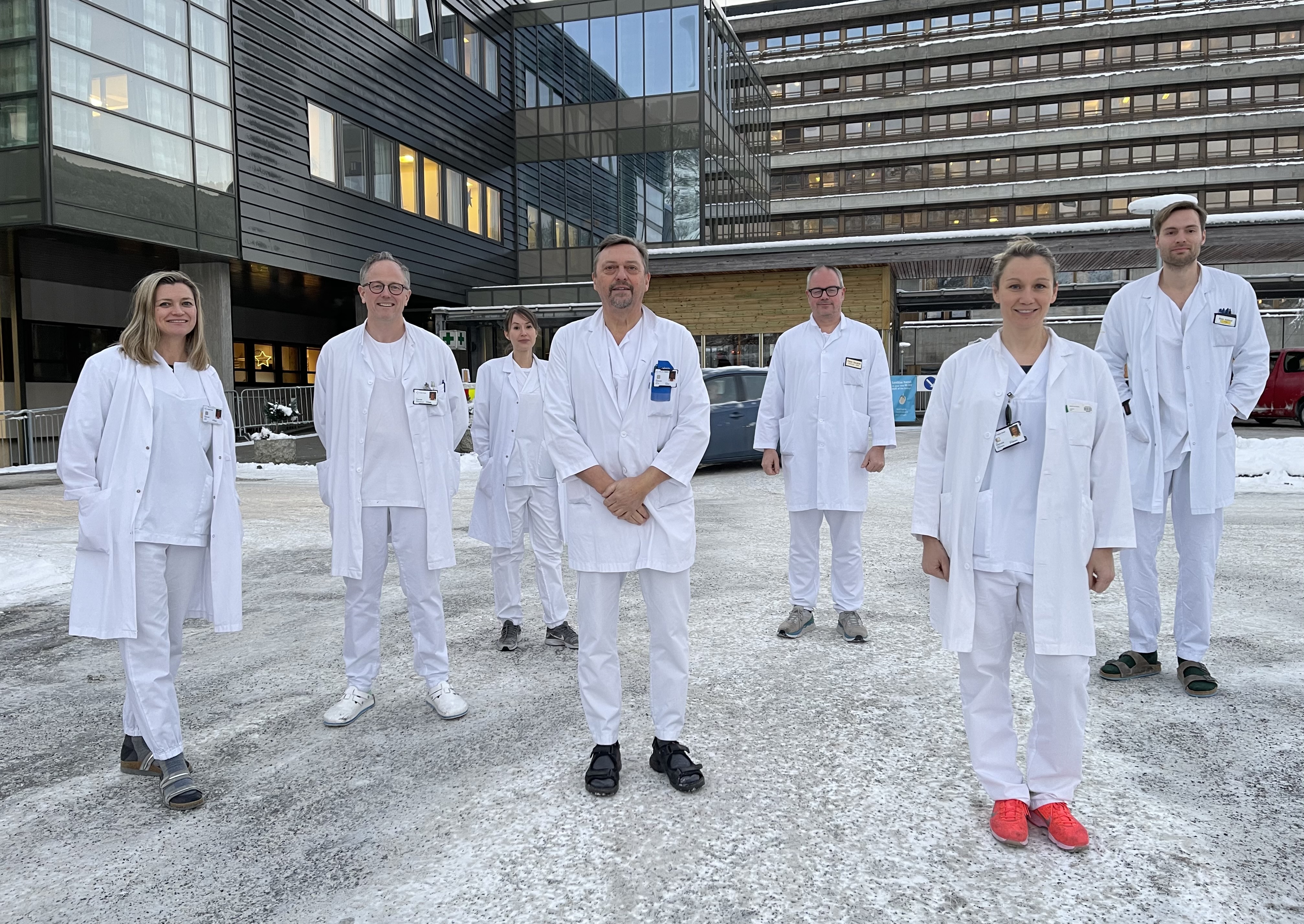 Sju kvitkledde legar som står samla utanfor sentralblokka