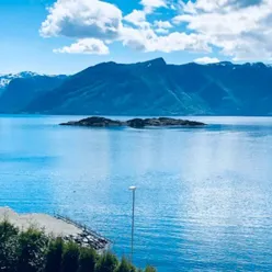 Fjord og fjellandskap som badar i sommarsol