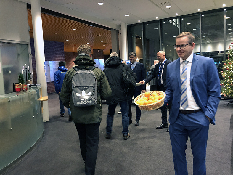 Dresskledde menn ved inngangspartiet som deler ut mandariner.