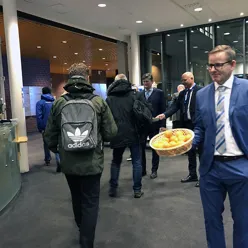 Dresskledde menn ved inngangspartiet som deler ut mandariner.